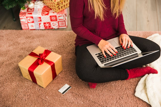 dame-mit-laptop-nahe-plastikkarte-und-geschenkboxen